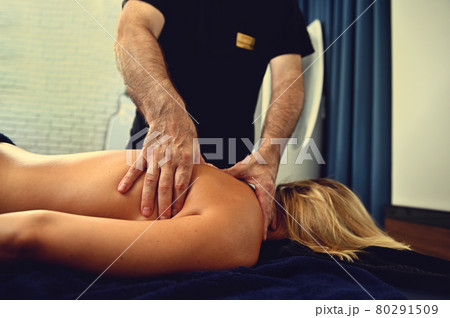Professional masseur working with the back of a wellness spa center client Professional masseur working with the back of a wellness spa center client 80291509