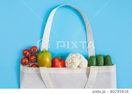 Zero waste concept. Vegetables in eco friendly reusable textile bag on blue background. Plastic free. Healthy fresh vegetarian food. Zero waste concept. Vegetables in eco friendly reusable textile bag on blue background. Plastic free. Healthy fresh vegetarian food. 80295616