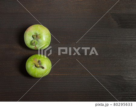 Trendy ugly food concept. Two green apples on a dark brown wooden background. Copy space. Fruit with a strange shape 80295633