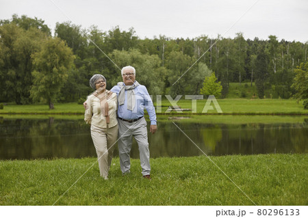 An elderly couple in casual clothes are walking outdoors 80296133