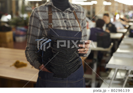 Cropped shot of a shoe factory worker holding a pile of leather footwear details 80296139