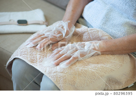 Senior woman wearing hand mask gloves. Moisturizing gloves to soften and protect hand skin. 80296395