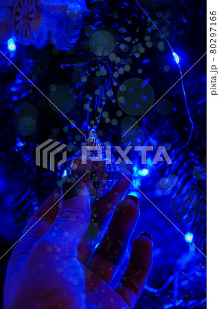 Female hand holding christmas tree decorations at night. Bright garland blue light. New Year magic moments. Fairytale Female hand holding christmas tree decorations at night. Bright garland blue light. New Year magic moments. Fairytale 80297166