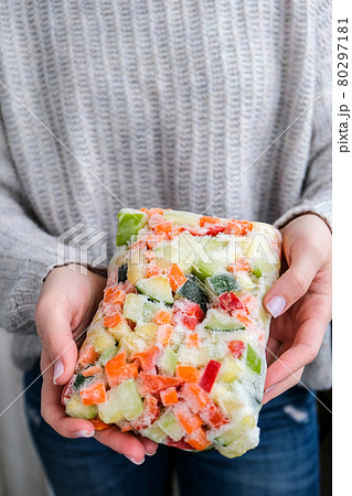 Mixed vegetable frozen food briquette in female hands. Preparing harvest for winter. Veganism, vegetarian healthy eating Mixed vegetable frozen food briquette in female hands. Preparing harvest for winter. Veganism, vegetarian healthy eating 80297181