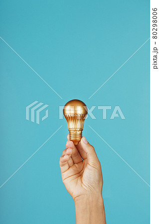 Gold light bulb in hand on a blue background, as a concept of ideas and assistance Gold light bulb in hand on a blue background, as a concept of ideas and assistance 80298006