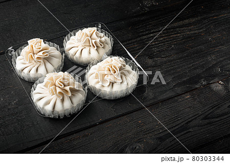Delicious baozi, Chinese steamed meat bun, in plastic tray, on black wooden table background, with copy space for text 80303344