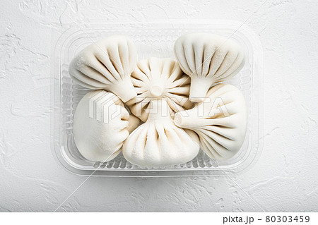 Khinkali Dumplings with beef and lamb meat, in plastic tray, on white stone surface, top view flat lay Khinkali Dumplings with beef and lamb meat, in plastic tray, on white stone surface, top view flat lay 80303459