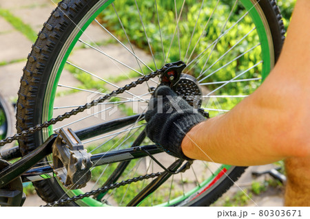 Bike mechanic man repairs bicycle in bicycle repair shop, outdoor. Hand of cyclist bicyclist examines, fixes modern cycle transmission system. Bike maintenance, sport shop concept. Bike mechanic man repairs bicycle in bicycle repair shop, outdoor. Hand of cyclist bicyclist examines, fixes modern cycle transmission system. Bike maintenance, sport shop concept. 80303671