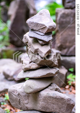 Close-up of a stack of stones in perfect balance in a mountain forest. Rock pyramid, rock balancing art. Meditation, balance, peace. Hobby. Vertical photo. 80305165