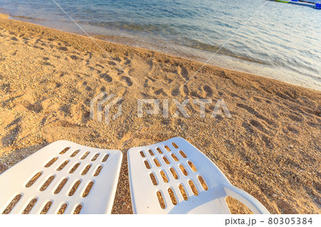Two beachchairs on the sand near sea, closeup Two beachchairs on the sand near sea, closeup 80305384