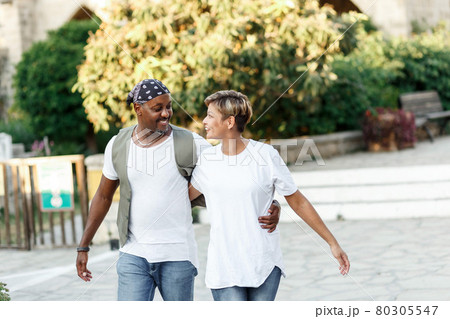 Mixed race smiling couple enjoying on vacation, tourist having fun walking and exploring city street during the day. holidays in diversity and love concept. Mixed race smiling couple enjoying on vacation, tourist having fun walking and exploring city street during the day. holidays in diversity and love concept. 80305547