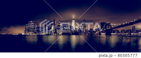 Manhattan bridge and New York City downtown skyline at night with skyscrapers illuminated over East River panorama. Manhattan bridge and New York City downtown skyline at night with skyscrapers illuminated over East River panorama. 80305777