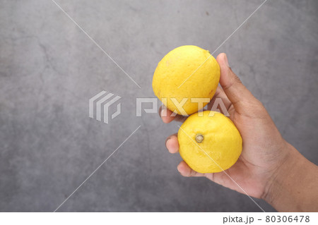 holding Yellow Lemon on black background  80306478