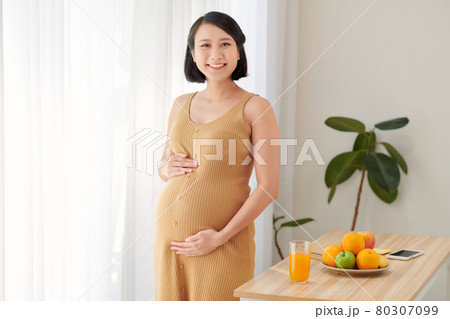 Beautiful pregnant woman standing near table with fresh vegetables 80307099