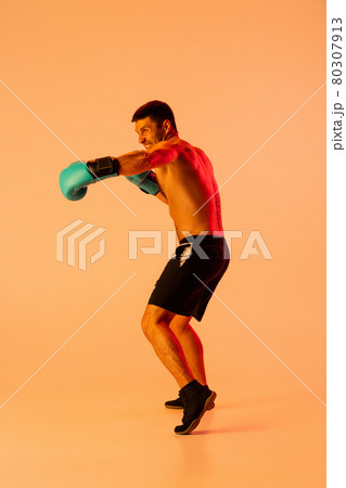One professional male boxer in sportswear and gloves isolated on yellow studio background in neon light. Concept of sport, activity, movement, wellbeing. 80307913