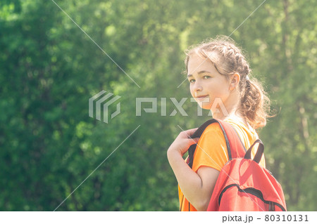 teenager girl in a bright t-shirt with backpack walks in nature 80310131