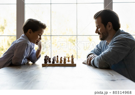 Focused thoughtful clever son and dad playing chess 80314968
