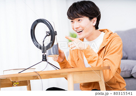 部屋でリングライトを使用しライブ配信する男性 80315541
