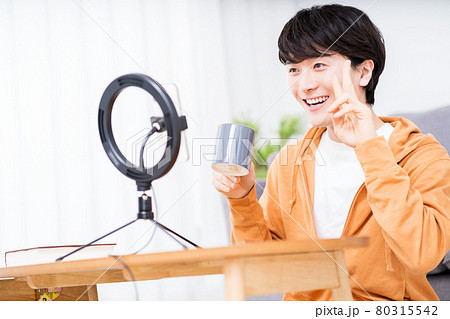 部屋でリングライトを使用しライブ配信する男性 部屋でリングライトを使用しライブ配信する男性 80315542