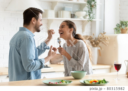 Cheery couple holding kitchenware singing having fun together in kitchen 80315982
