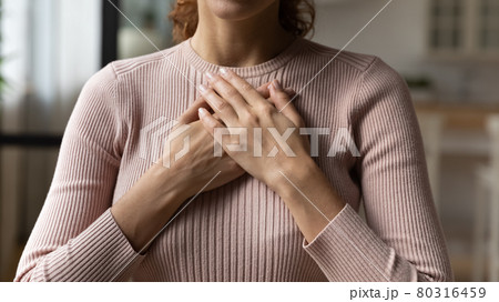 Young woman holding folded hands on chest heart. Young woman holding folded hands on chest heart. 80316459