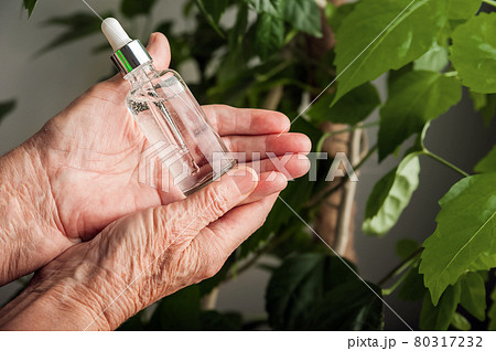 Serum in wrinkled hands and copy space. Skincare, anti-aging cosmetics, healthcare concept. Top view. 80317232