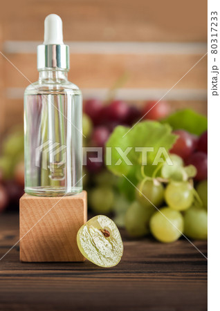 Serum on wooden trending podium and grapes in cut. Skincare, healthcare concept from grape seed oil. Top view. 80317233
