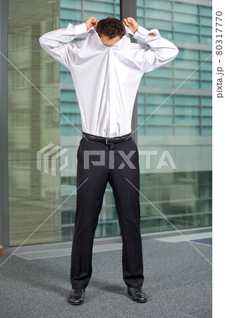 Businessman removing shirt at office Businessman removing shirt at office 80317770