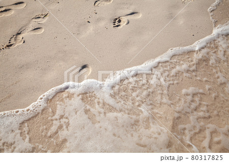Footprints of bare feet are over a wet sand on the beach 80317825