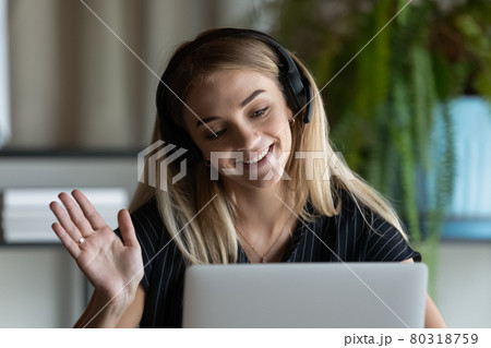 Close up businesswoman in headphones waving hand at laptop webcam Close up businesswoman in headphones waving hand at laptop webcam 80318759
