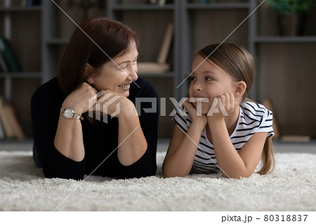 Happy granny and granddaughter kid resting together on heating floor Happy granny and granddaughter kid resting together on heating floor 80318837