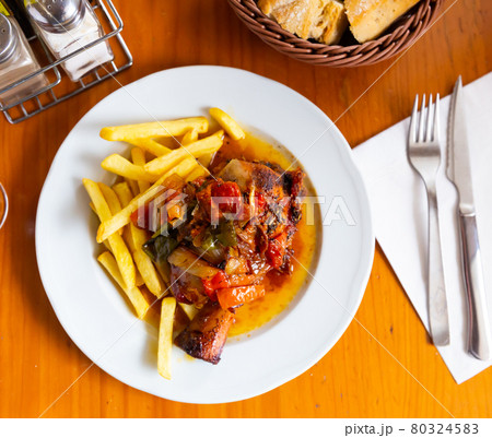 Tasty pork knuckle with potatoes and stewed peppers served 80324583
