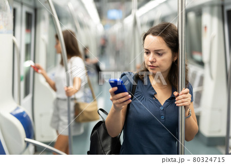 Woman with phone traveling in subway car Woman with phone traveling in subway car 80324715
