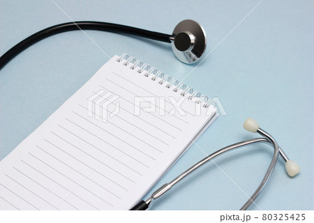The doctor's workplace. A stethoscope and a notebook for writing with a clean page. 80325425