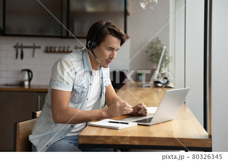 Focused young man in wireless headset holding video call. 80326345