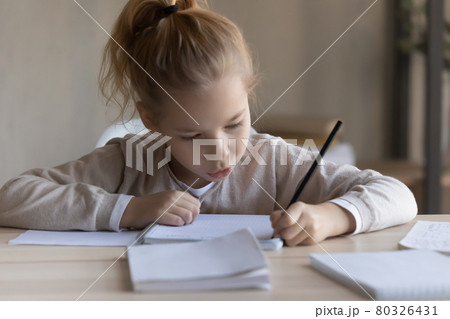 Little preteen girl study foreign language writing classwork at desk Little preteen girl study foreign language writing classwork at desk 80326431