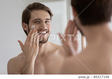 Happy relaxed satisfied handsome young man applying collagen cream Happy relaxed satisfied handsome young man applying collagen cream 80327198