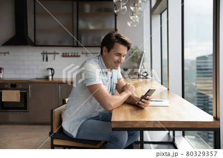 Happy young handsome man using smartphone in office kitchen. Happy young handsome man using smartphone in office kitchen. 80329357