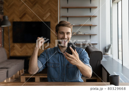 Overjoyed emotional young man celebrating online lottery win. 80329668
