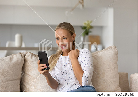 Excited woman holding smartphone, reading good news, celebrating success 80329669