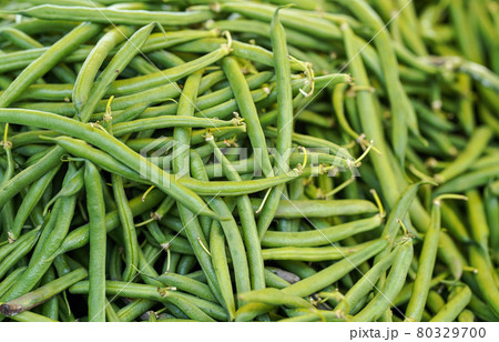 Pile green string beans displayed on food market. Abstract healthy nutrition background - shallow depth of field photo, only few hulls in focus Pile green string beans displayed on food market. Abstract healthy nutrition background - shallow depth of field photo, only few hulls in focus 80329700