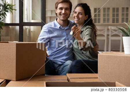 Bonding couple sit on couch holding keys celebrate moving day Bonding couple sit on couch holding keys celebrate moving day 80330508