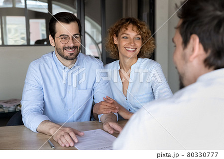 Happy young couple listening to manager at meeting in office Happy young couple listening to manager at meeting in office 80330777