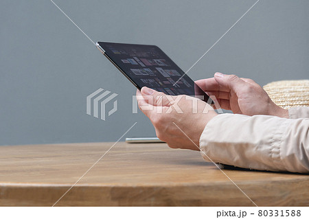 A woman is sitting at a table in a cafe with a tablet in her hands. 80331588