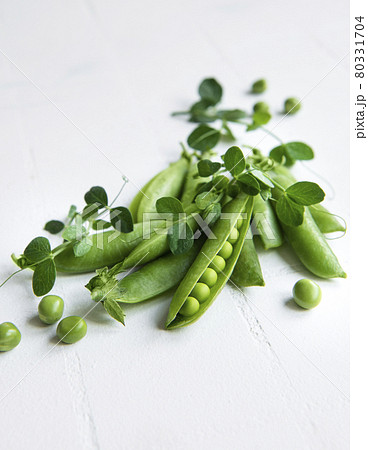 Fresh green peas pods and green peas with sprouts on white tile background. Fresh green peas pods and green peas with sprouts on white tile background. 80331704