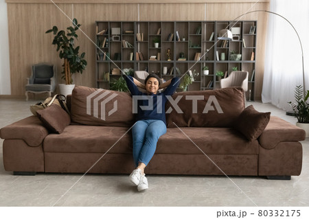 Calm Indian woman relax on sofa breathe fresh air 80332175