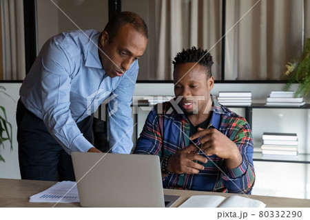 African American mentor teaching intern, pointing at laptop screen African American mentor teaching intern, pointing at laptop screen 80332290