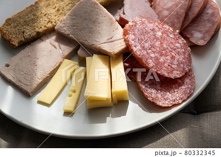 sliced smoked pork, bread, sausage, cheese on plate 80332345
