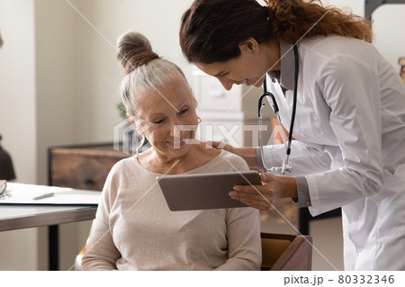Female doctor use tablet at consultation with mature patient 80332346