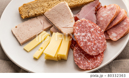 sliced smoked pork, bread, sausage, cheese on plate 80332363